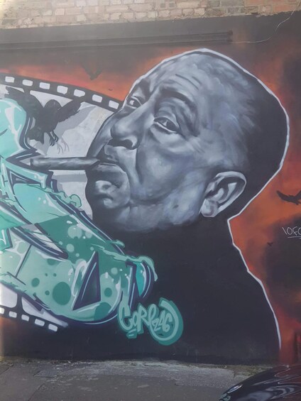A mural with a person holding a film strip, graffiti, and a car. 3