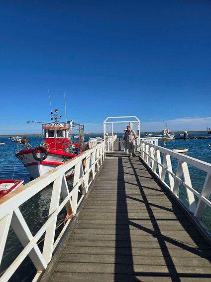 A wooden pier leading to a dock with boats moored on both sides. 5