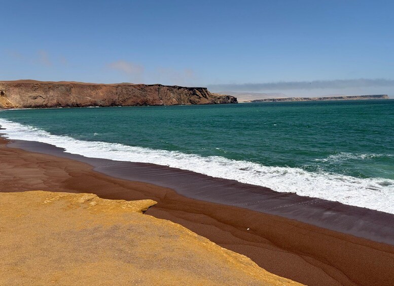 A beach with golden sand, turquoise sea, and rocky cliffs. 1