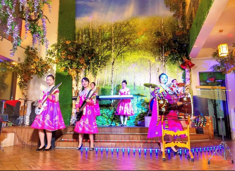 A stage with performers in traditional attire, a keyboard, drums, and a guitar. 1
