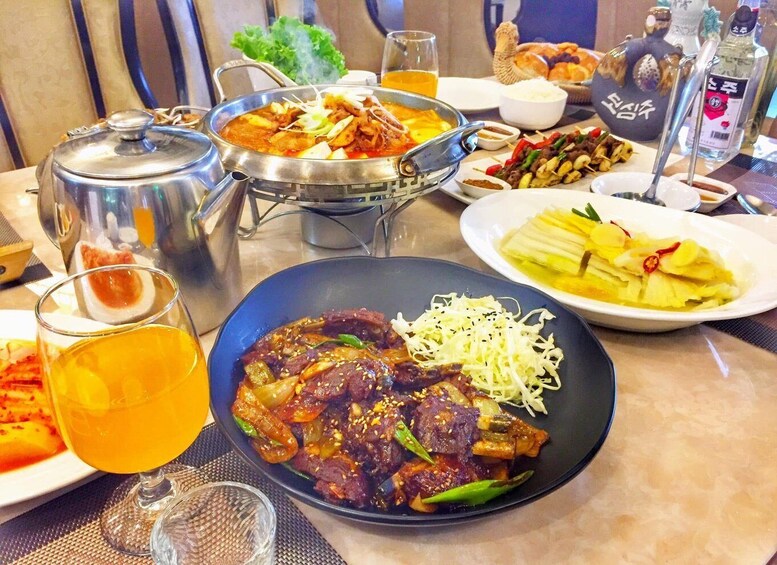 A table with a variety of dishes, including a bowl of beef stew, a plate of sliced vegetables, and a glass of beer. 3