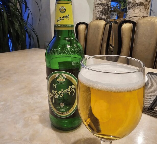 A bottle of beer and a glass of beer on a table. 5