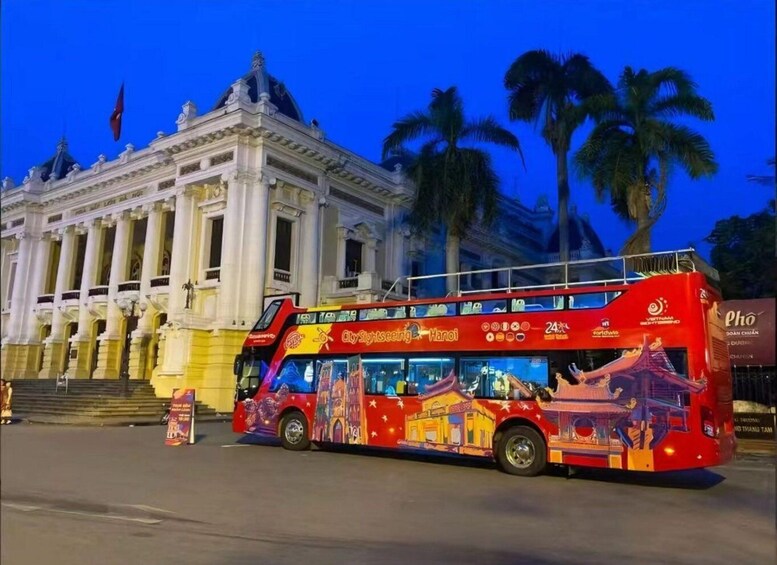 A red double-decker bus with 'City Sightseeing Hanoi' written on it parked in front of a white building with columns. 1