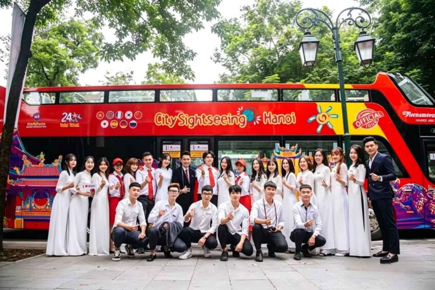 A group of people posing in front of a red CitySightseeing bus with 'Hanoi' written on it. 2
