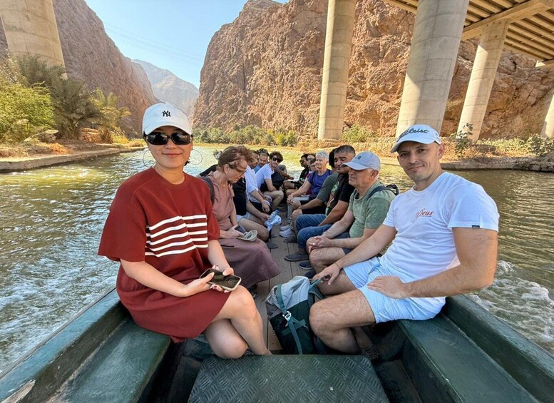 A group of people on a boat under a bridge with rocky cliffs in the background. 5