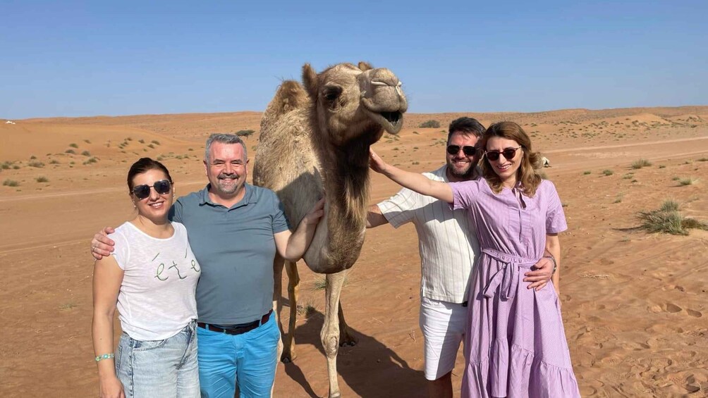 A group of people with a camel in a desert landscape. 1