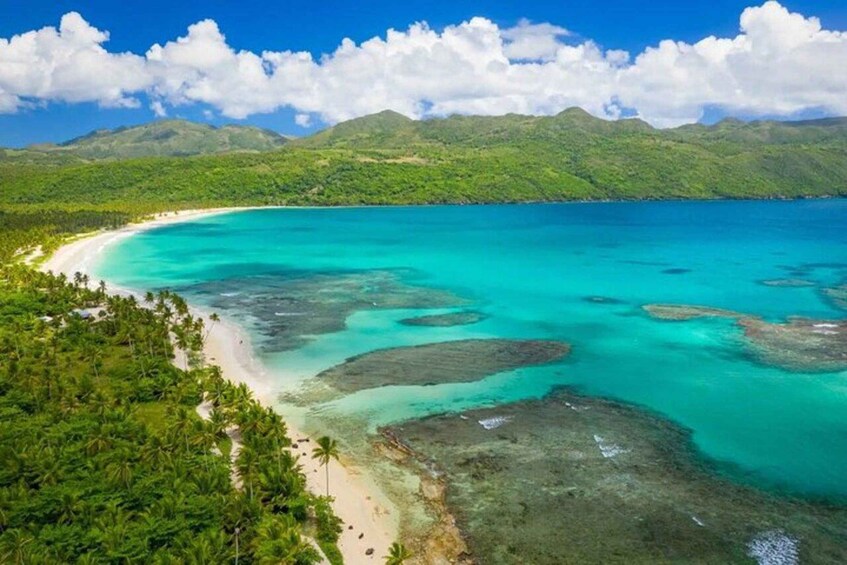 A tropical beach with clear turquoise waters, white sand, and lush greenery. 1