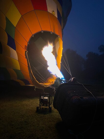 A hot air balloon with flames inside, tethered to a ground vehicle. 2