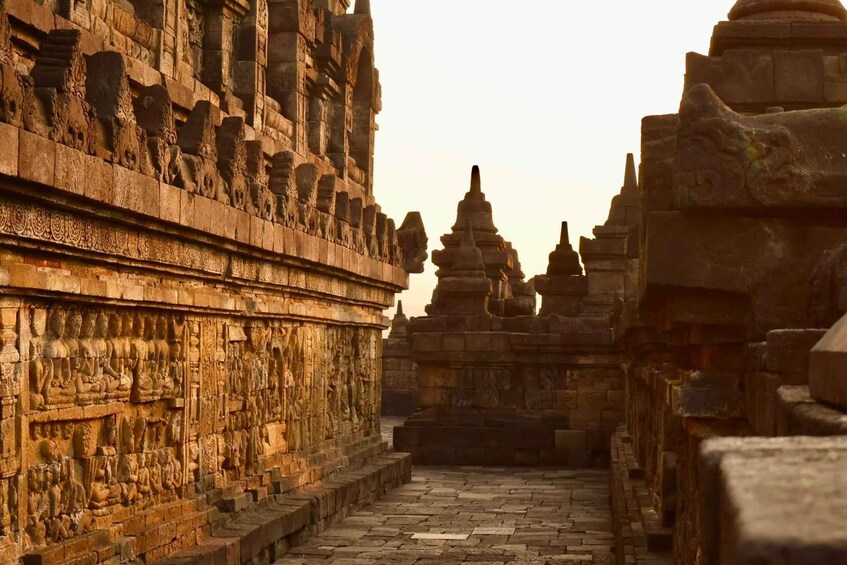 An ancient stone pathway flanked by intricately carved stone structures, leading towards a distant temple. 3