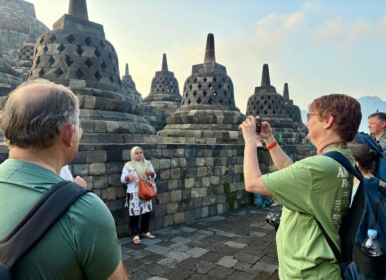Tourists taking photos of ancient stone structures with intricate patterns. 1