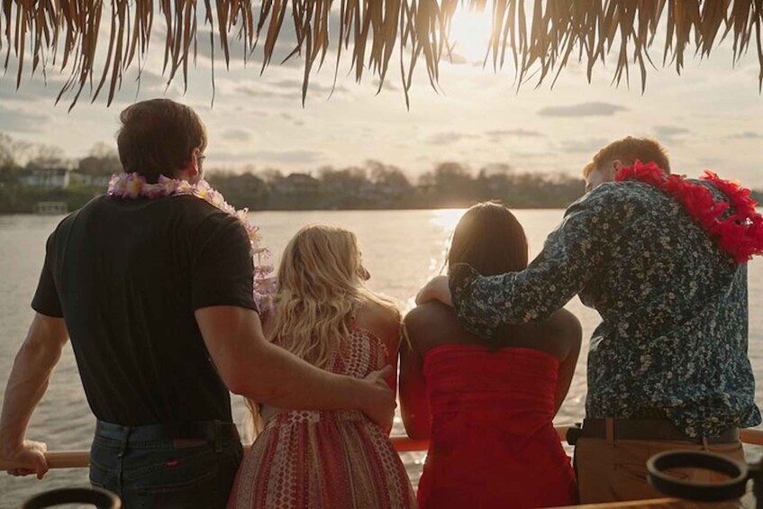 A group of people on a boat with a sunset in the background. 5