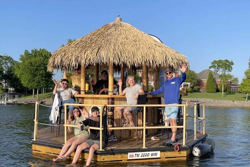 A group of people on a floating platform with a thatched roof, surrounded by water and greenery. 1
