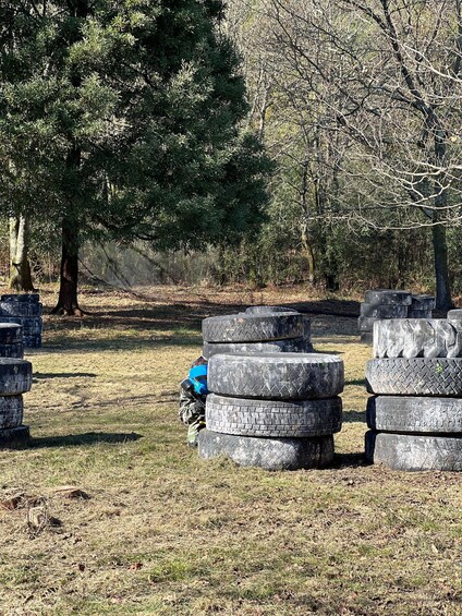 A forest with stacks of tires and a person in camouflage gear. 3
