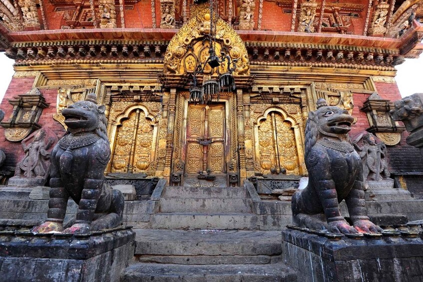 A temple entrance with ornate golden doors and stone lion statues. 3