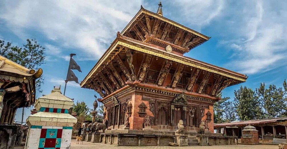 A traditional multi-tiered wooden structure with intricate carvings, surrounded by trees and a clear sky. 1
