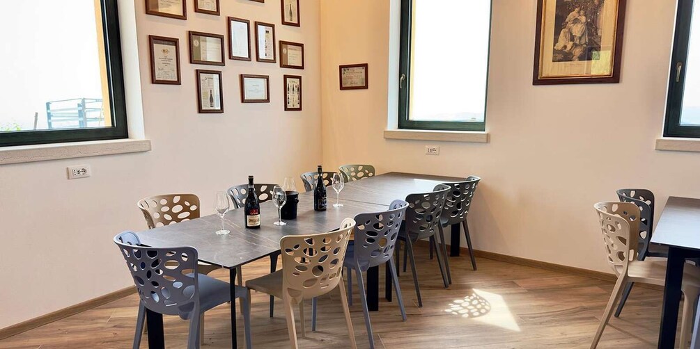 A dining room with a wooden table, six chairs, and framed certificates on the wall. 4