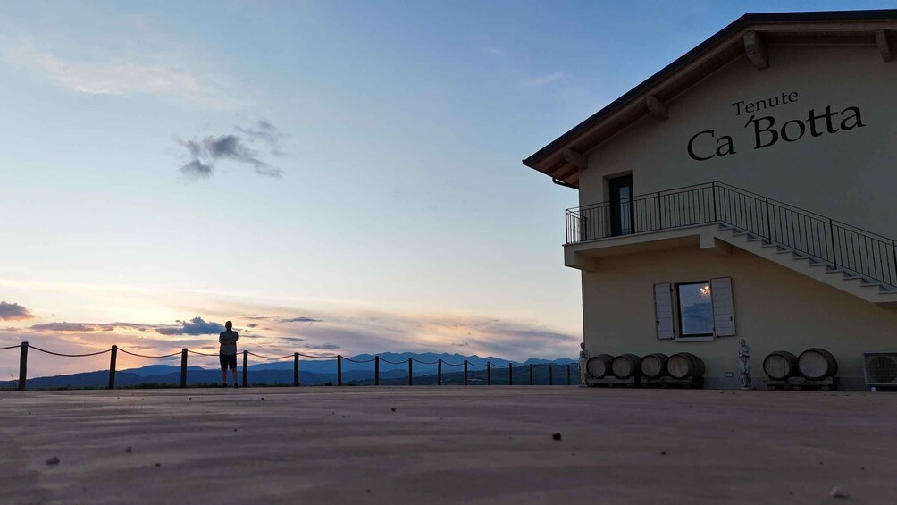 A building named 'Tenute Ca' Botta' with a staircase and a person standing by a fence. 1