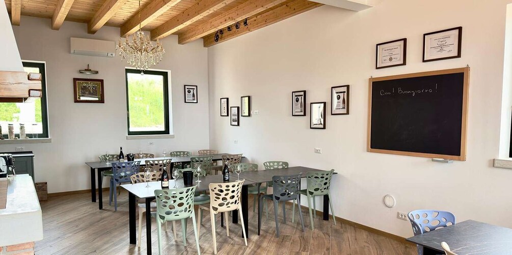 A dining area with multiple tables and chairs, a blackboard with writing, and framed pictures on the walls. 5