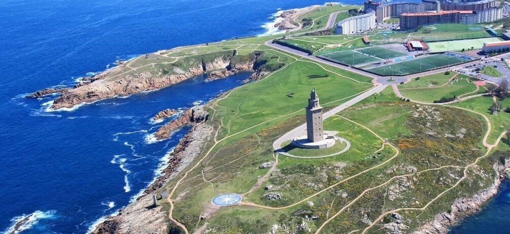 A coastal landscape with a lighthouse, grassy areas, and a building complex. 5
