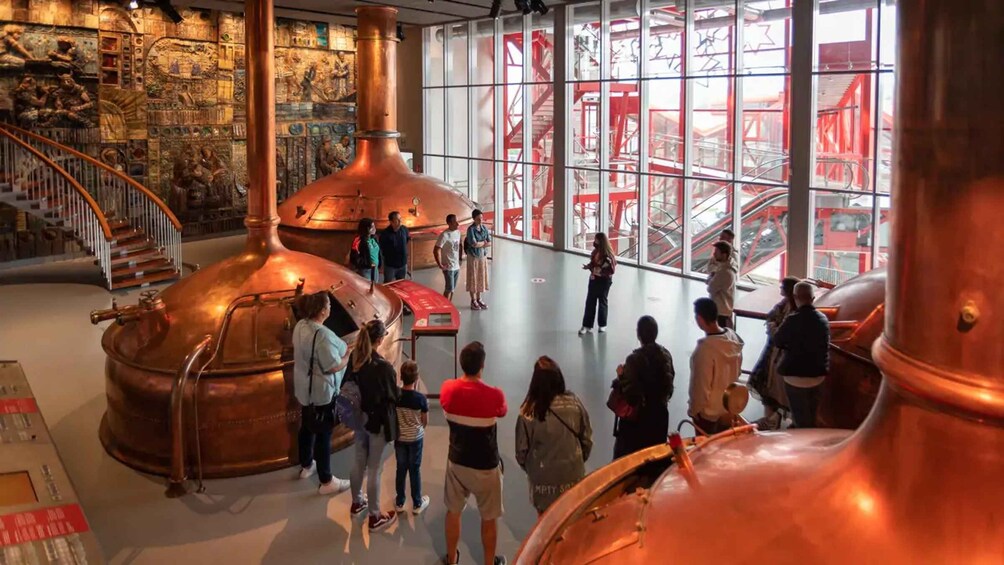 A museum interior with copper distillation equipment and a staircase. 1