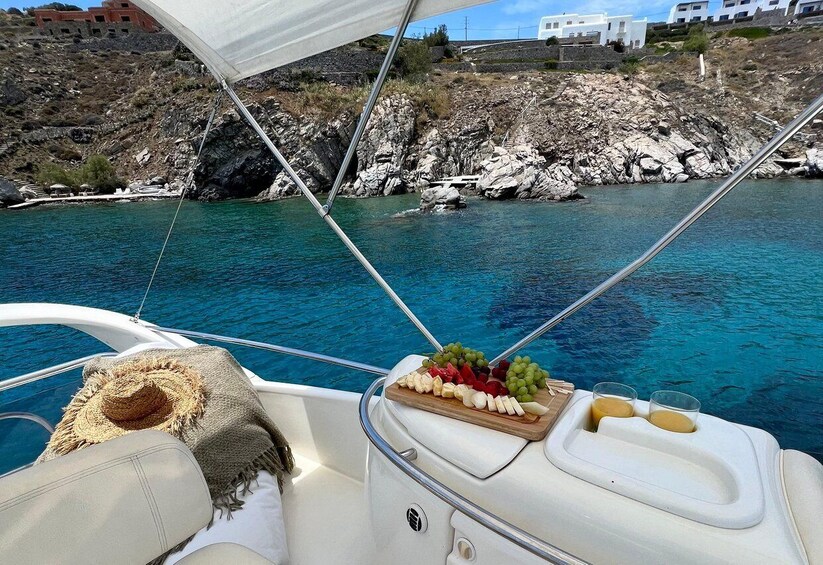 A boat with a white interior, a hat, and a fruit platter with grapes and cheese. 5
