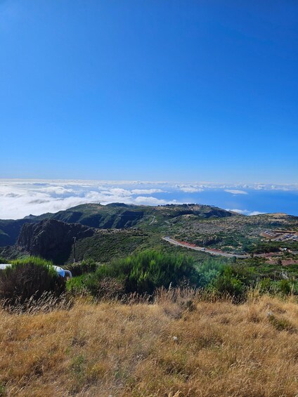 A mountainous landscape with a winding road, green vegetation, and a clear blue sky. 2