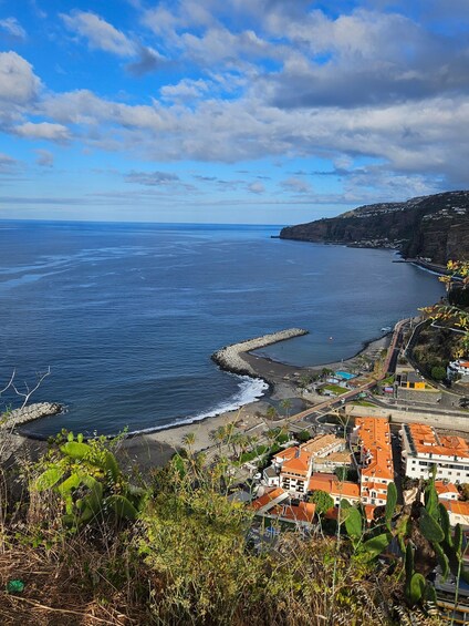 A coastal town with a rocky shoreline, buildings with red roofs, and a clear blue sky. 3