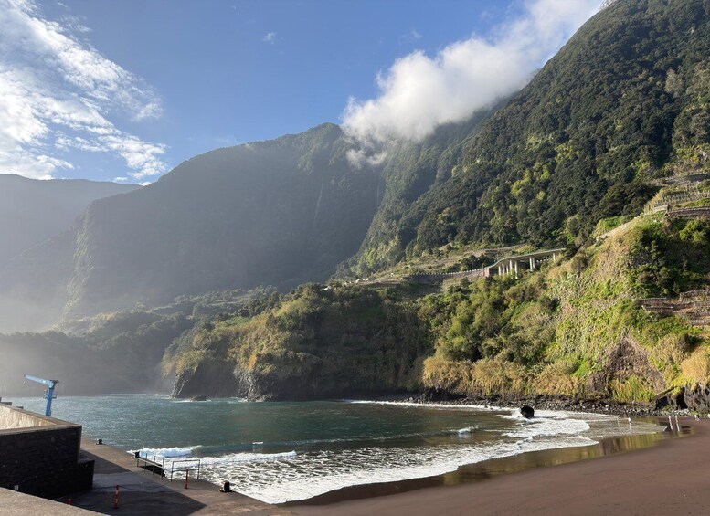 A coastal landscape with a beach, waves, and a mountainous backdrop. 5