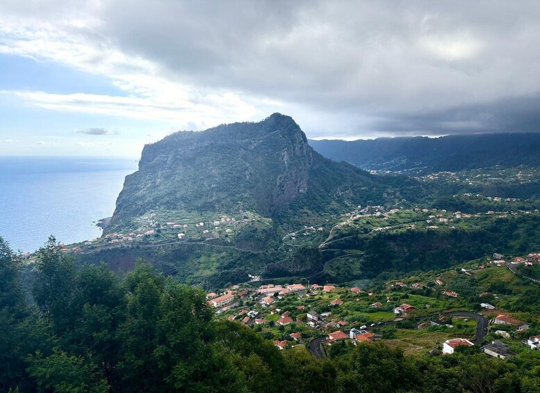 A coastal town with a prominent mountain peak, lush greenery, and a winding road. 3