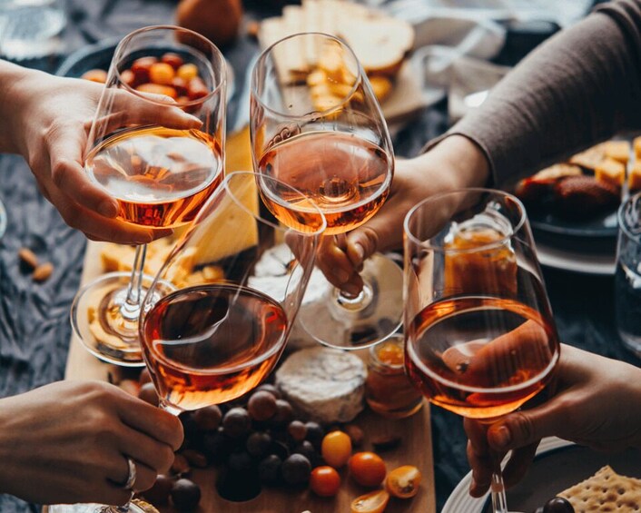 A group of people toasting with wine glasses, surrounded by cheese and fruits. 2