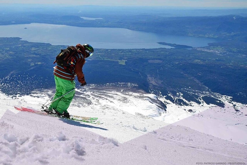 A skier on a snowy mountain with a lake in the background. 3
