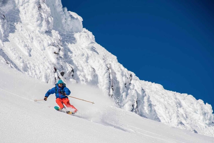 A skier in bright clothing descending a snowy slope. 1