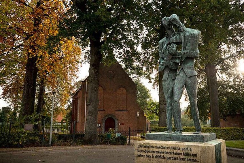 A statue of a man and woman embracing, a brick building, and trees with autumn leaves. 5