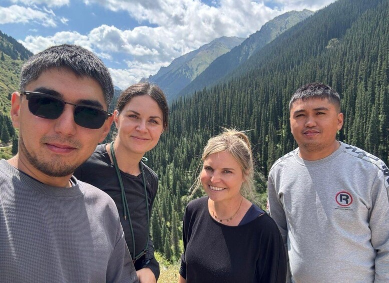 Four people standing in a forested mountainous area. 5