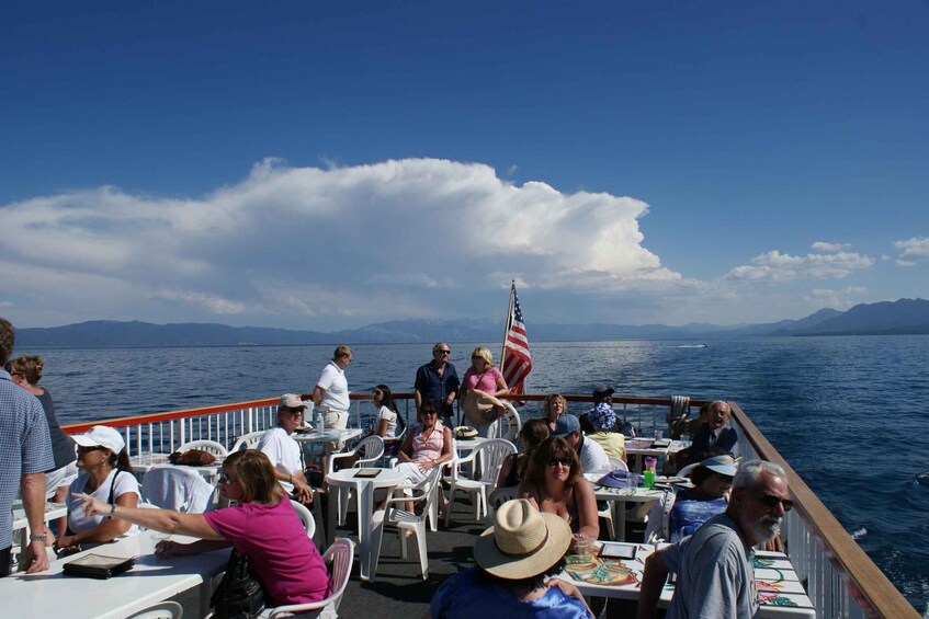 People dining on a boat with a view of the sea and mountains in the background. 2