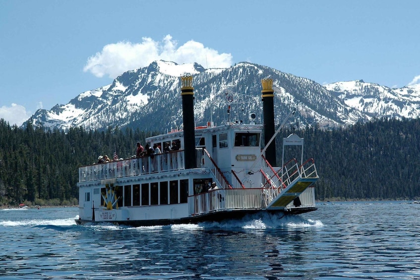 A riverboat with passengers, a mountainous backdrop, and a clear sky. 3