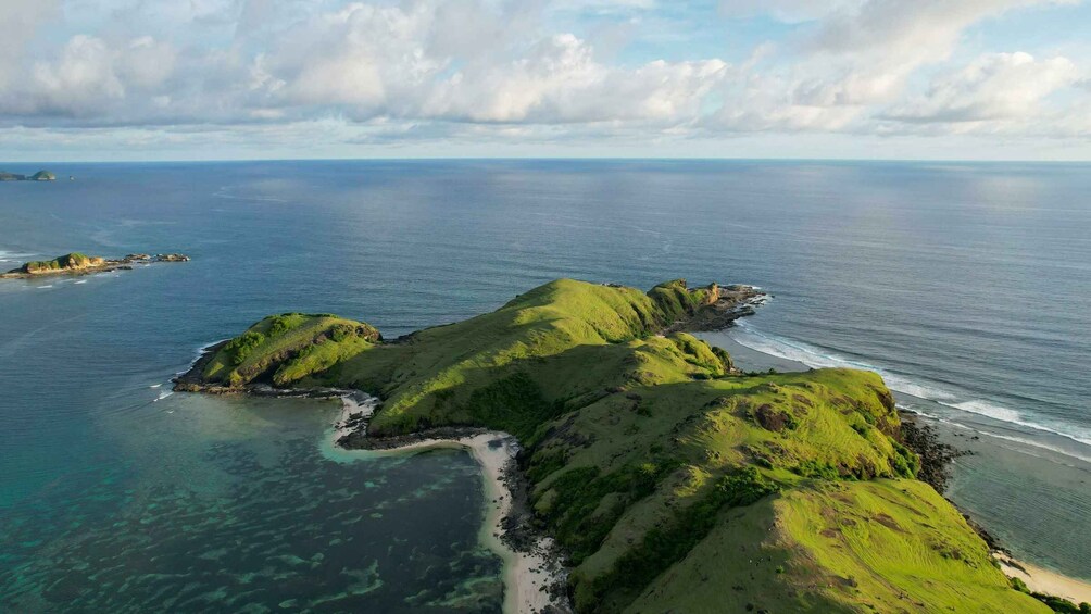 A coastal landscape with green hills, clear blue sea, and distant islands. 5