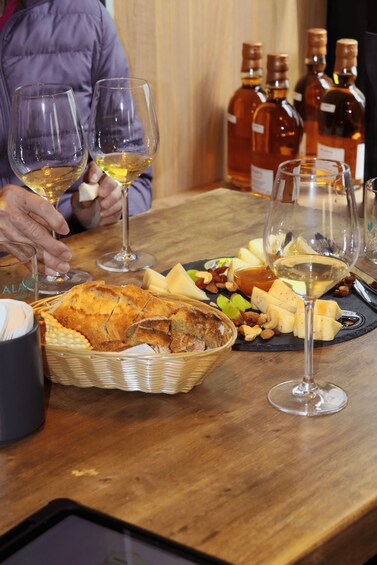 A table with wine glasses, cheese, nuts, and bread. 1