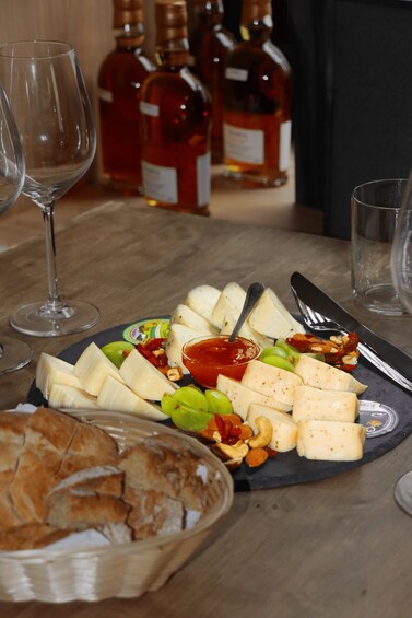 A cheese platter with various cheeses, nuts, and a small bowl of sauce on a slate board. 3