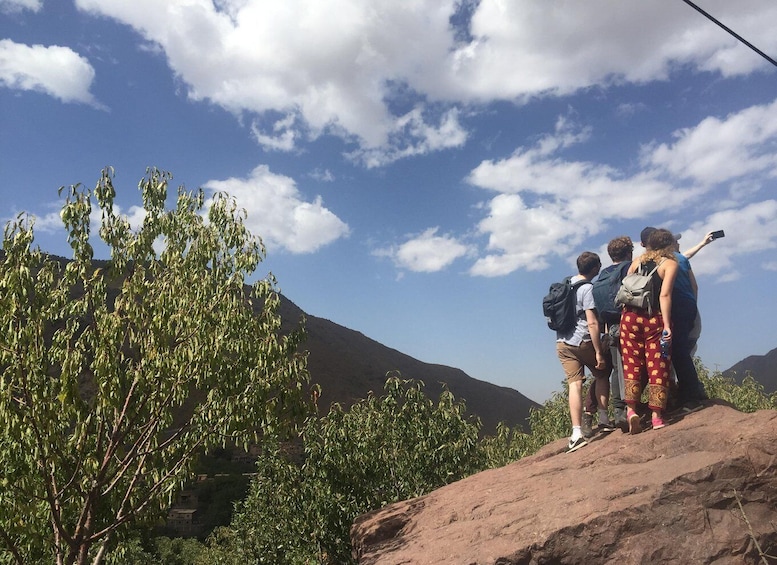 A group of hikers on a rocky outcrop with a mountain in the background. 2