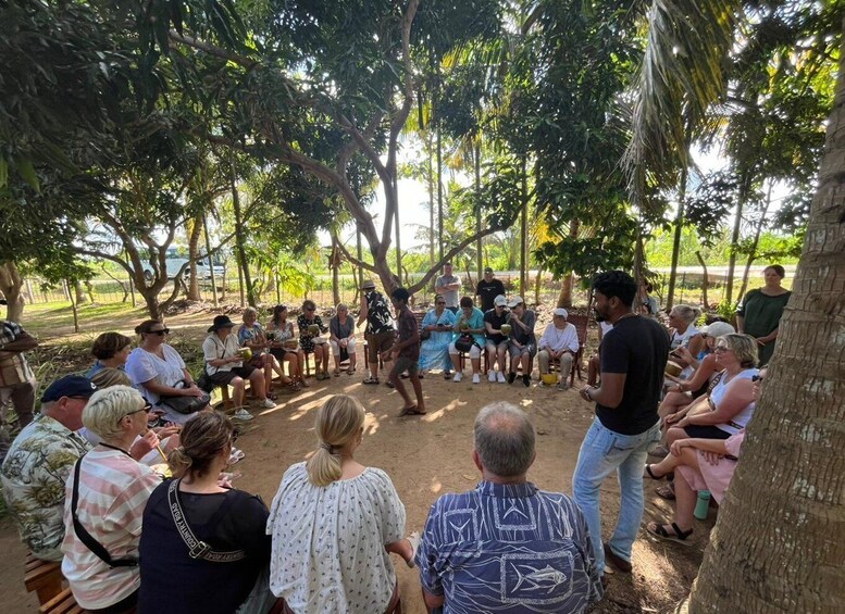 A group of people seated in a circle outdoors, engaged in a discussion or presentation. 5
