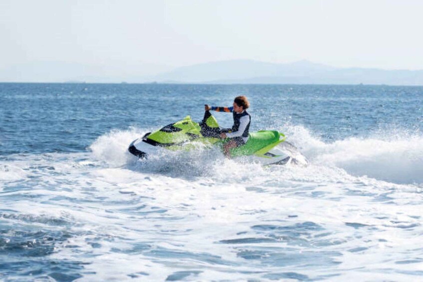 A person riding a green jet ski on the ocean. 5