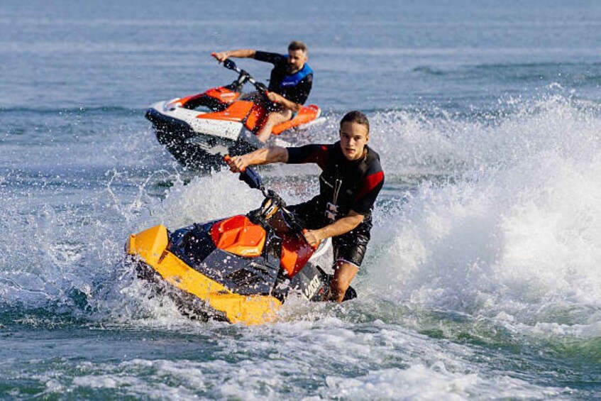Two people jet-skiing on a body of water. 1