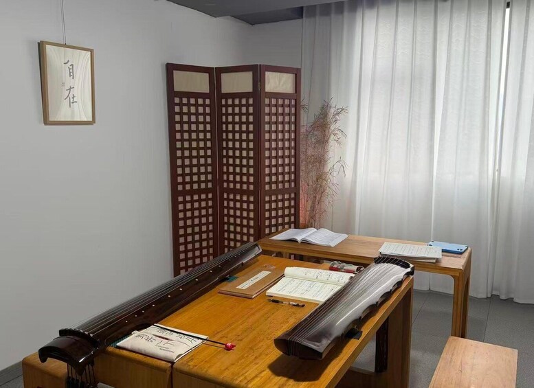 A traditional Japanese room with tatami flooring, a shoji screen, and a tatami mat table with calligraphy and a book. 4