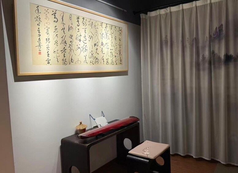 A room with a large calligraphy piece on the wall, a traditional Japanese desk, and a curtain with a forest design. 1