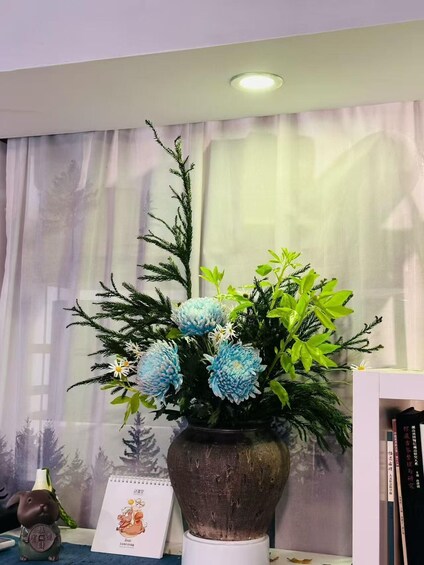 A vase with blue flowers and green foliage on a table. 2