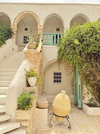 A courtyard with stone steps, arches, potted plants, and a traditional clay pot. 2