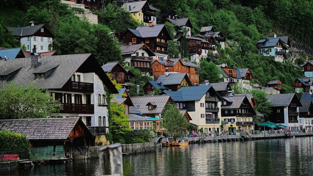 A cluster of traditional wooden houses on a hillside by a calm river. 2