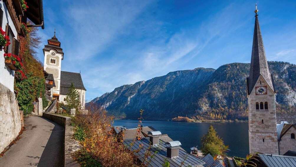 A town with a church tower and a steeple, a river, and mountains in the background. 3
