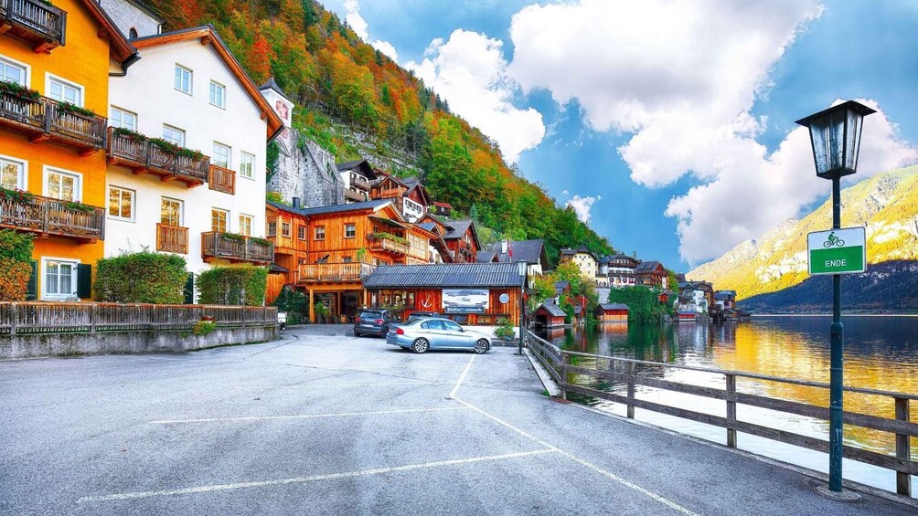 A lakeside town with colorful buildings, a parked car, and a sign indicating a bike path. 5